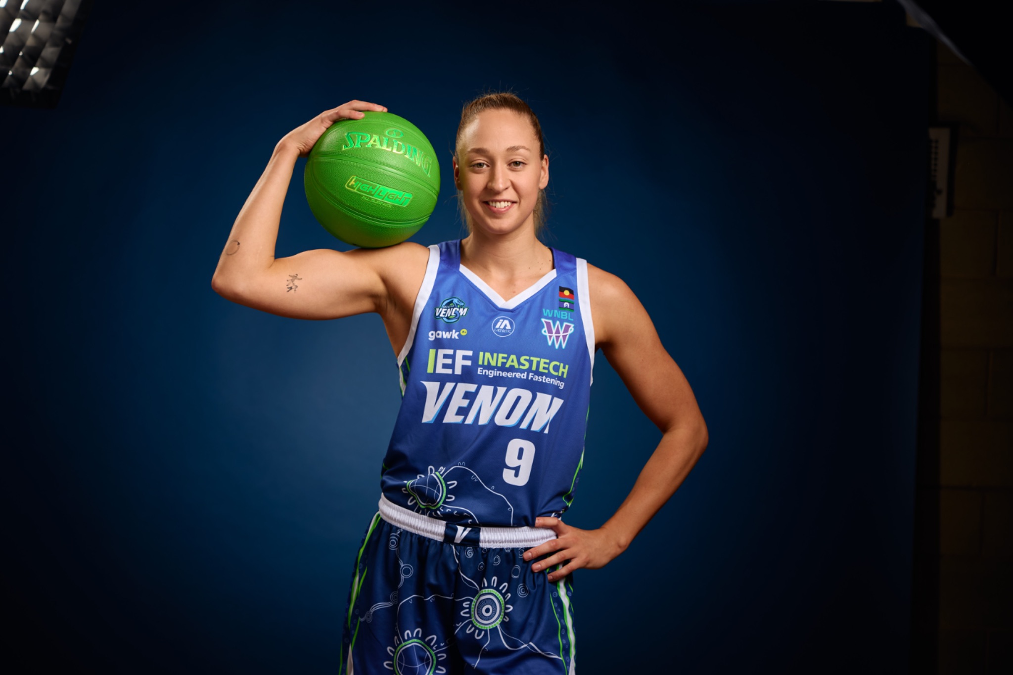 Geelong Venom player holding a green basketball in a studio portrait