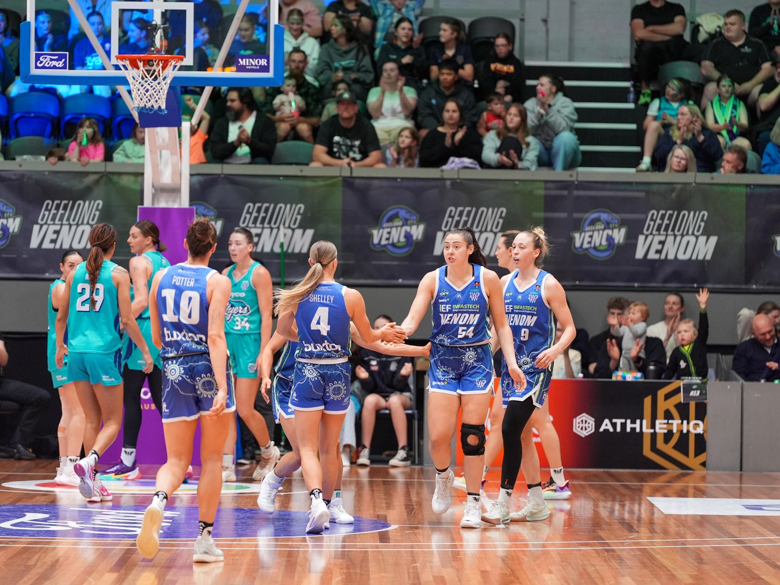 Geelong Venom players celebrating with a high-five during a WNBL home game